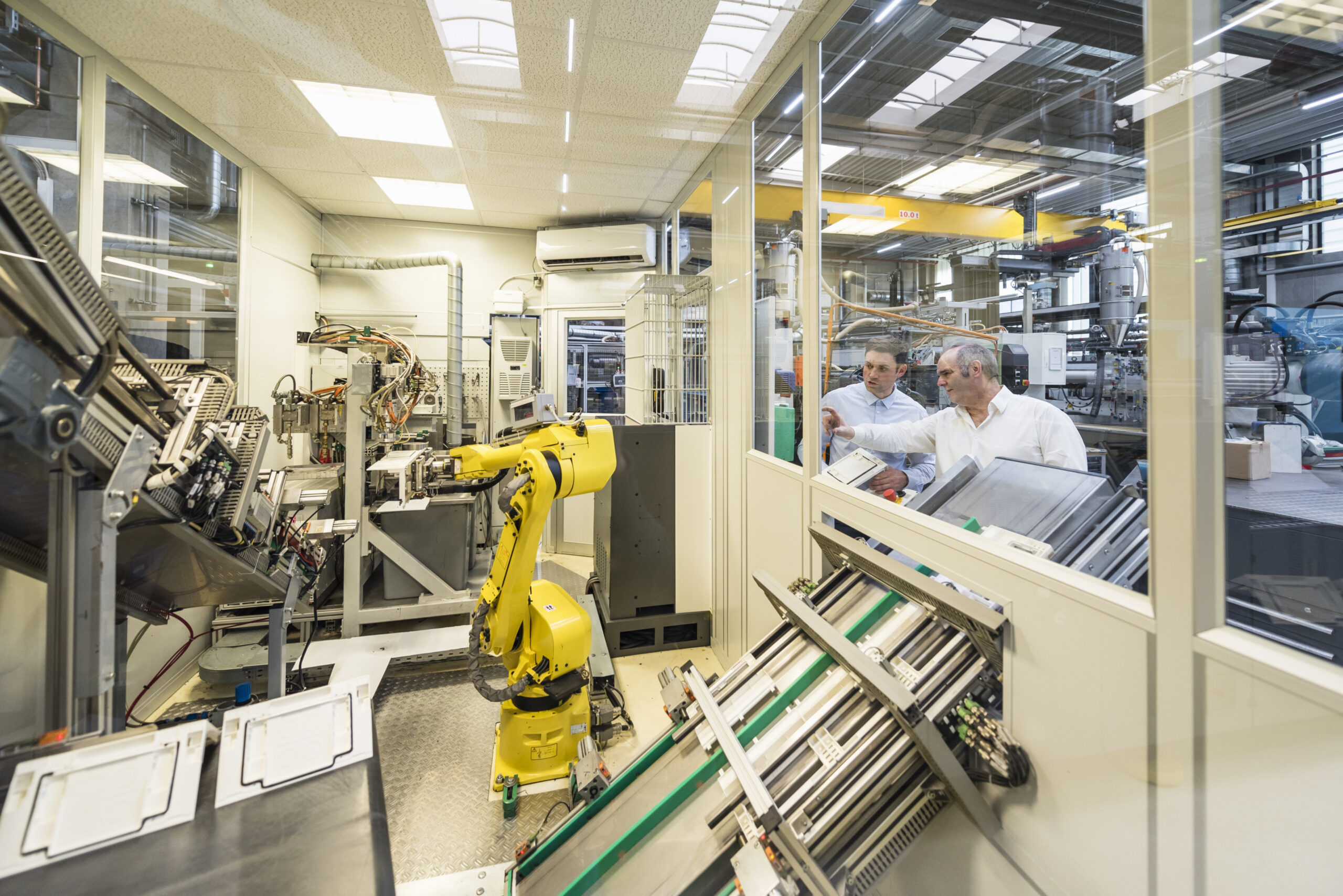 Two men talking in factory shop floor looking at industrial robot