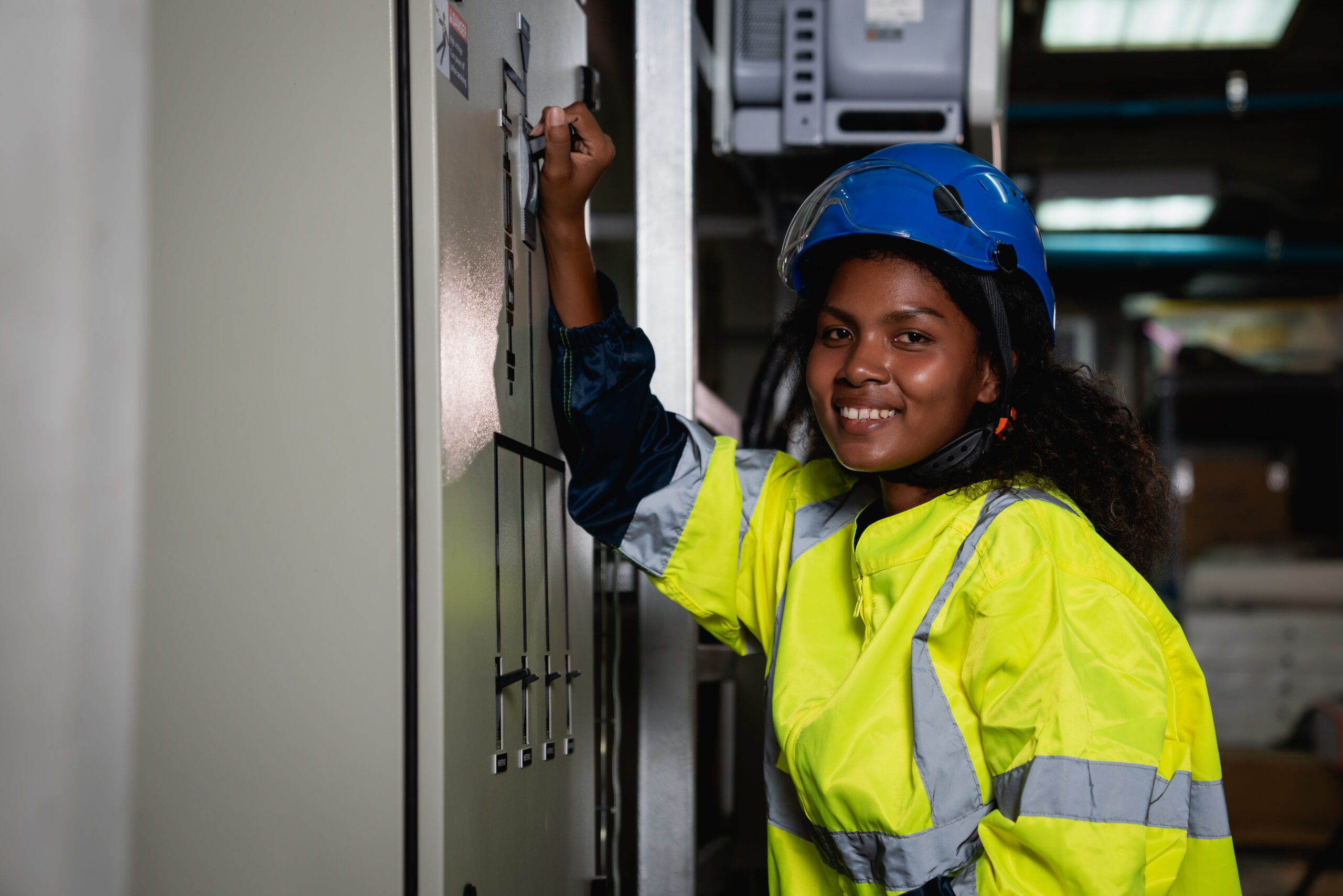 SMED Technician in a yellow and blue safety vest is working on a panel
